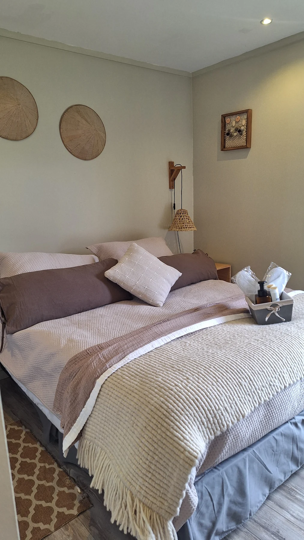Dormitorio matrimonial con ropa de cama, almohadas y detalles sobre las mesas de noche