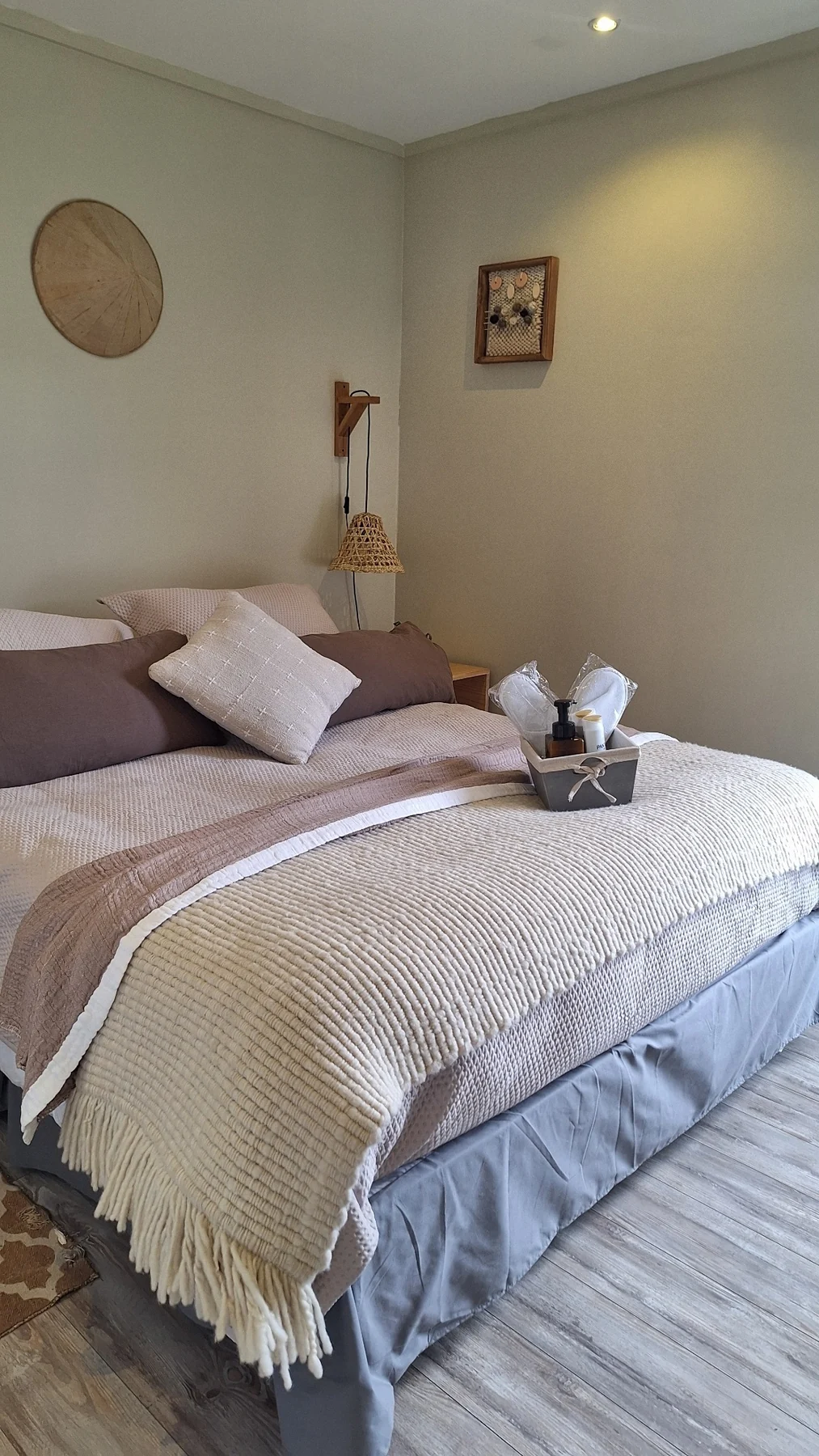 Cama matrimonial con manta tejida y cojines, vista desde arriba